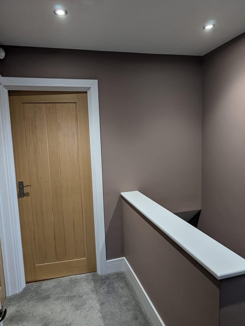 Freshly painted hallway with grey carpet and wood door