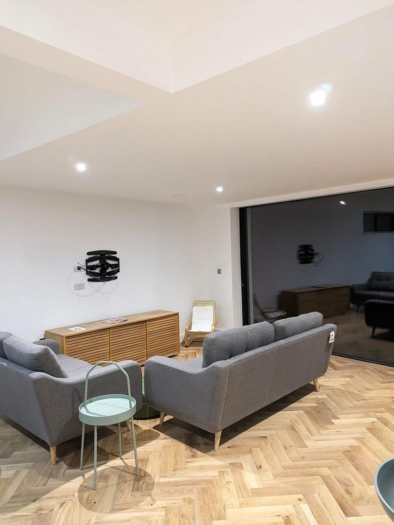 Freshly decorated open plan lounge with pale walls and herringbone floor