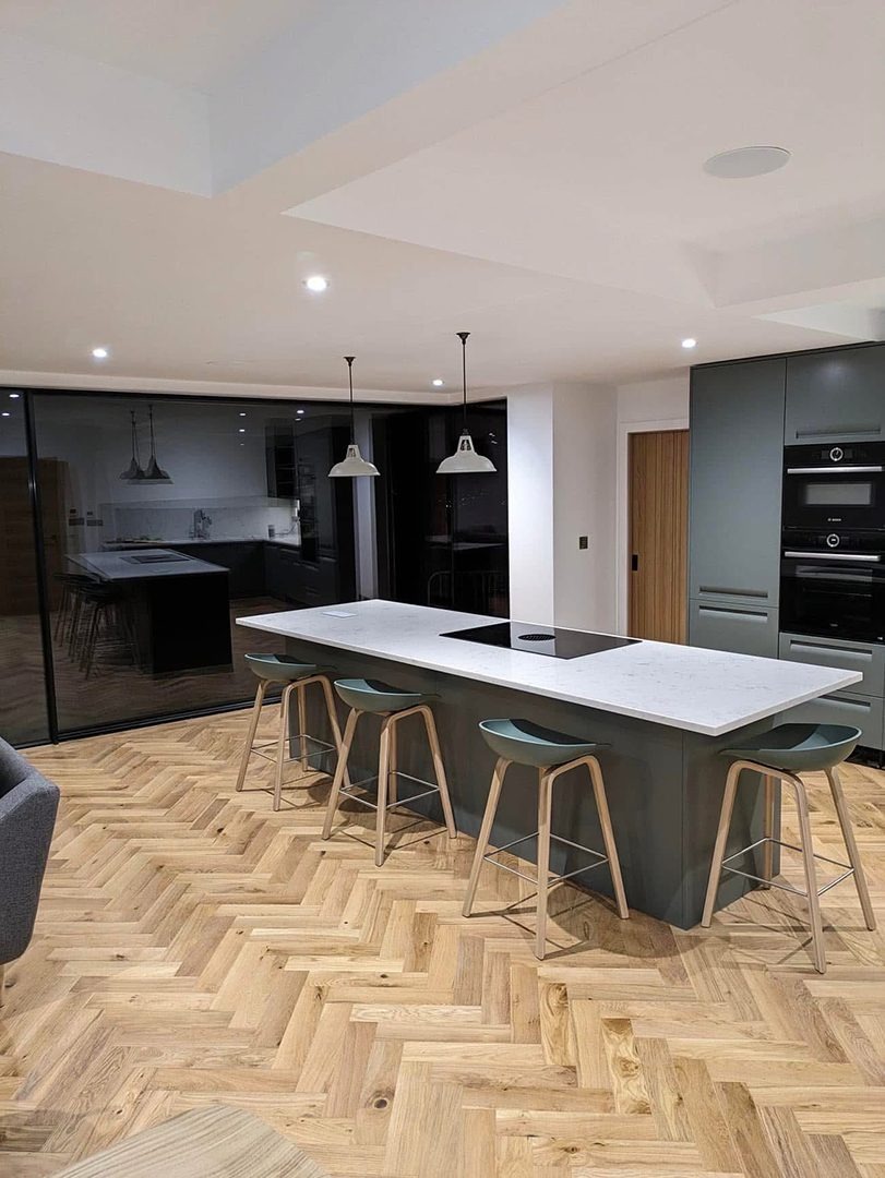 Freshly decorated open plan kitchen with island and herringbone floor